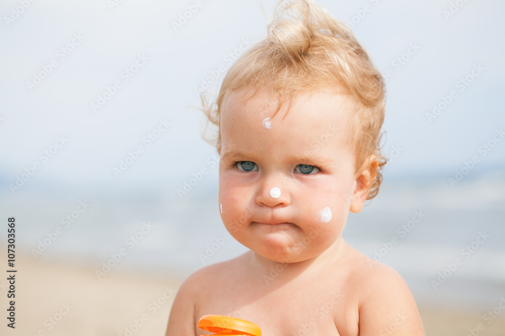Adorable girl at beach applying sunblock cream Adorable girl at beach applying sunblock cream