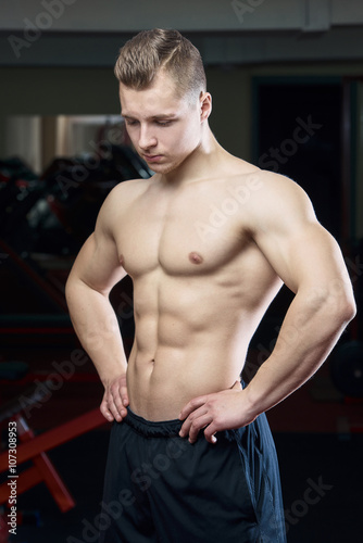 Tired muscular man posing topless in the gym