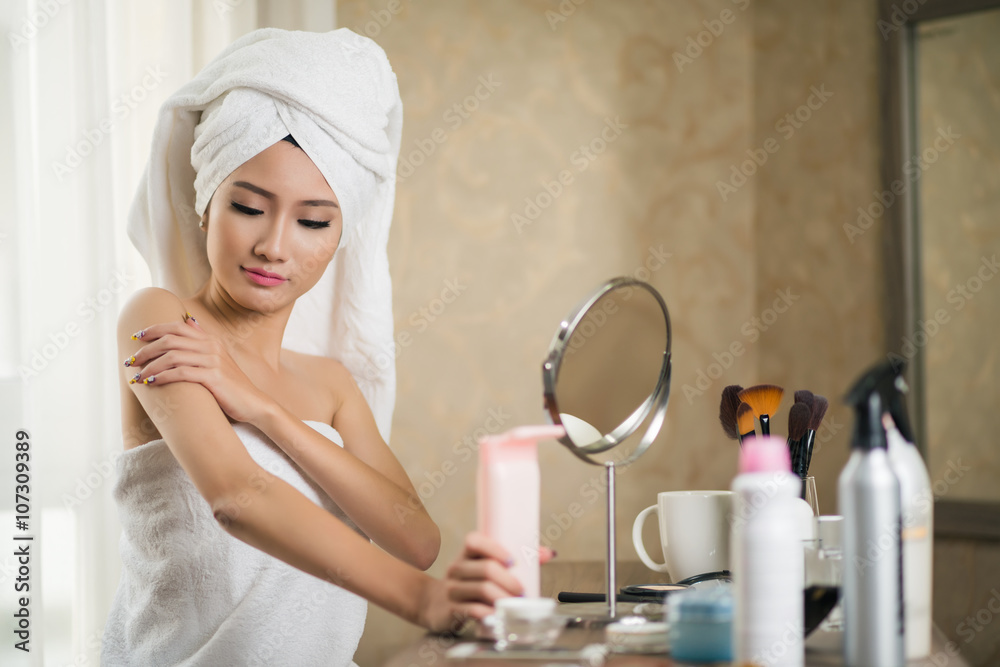 Beautiful Asian woman applying lotion after shower Beautiful Asian woman applying lotion after shower