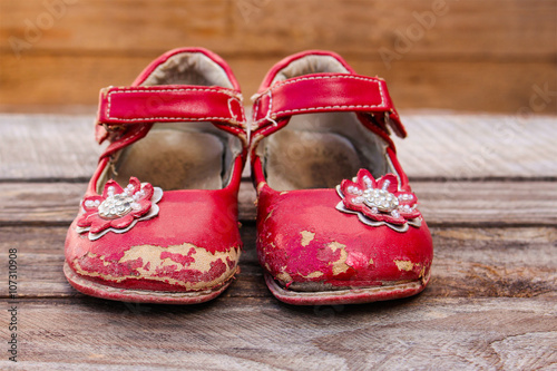 Fotografie Old red baby shoes on wooden background.