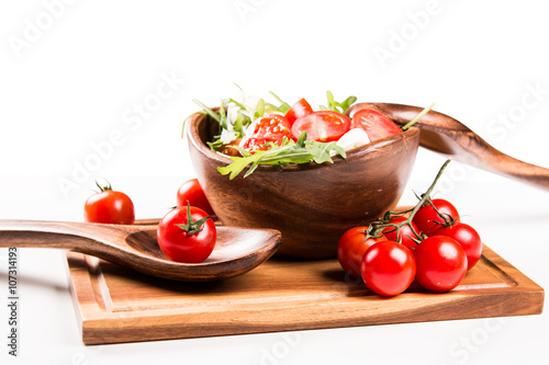 salad in a wooden salad bowl. Tomato, mozzarella and basil isolated on white background