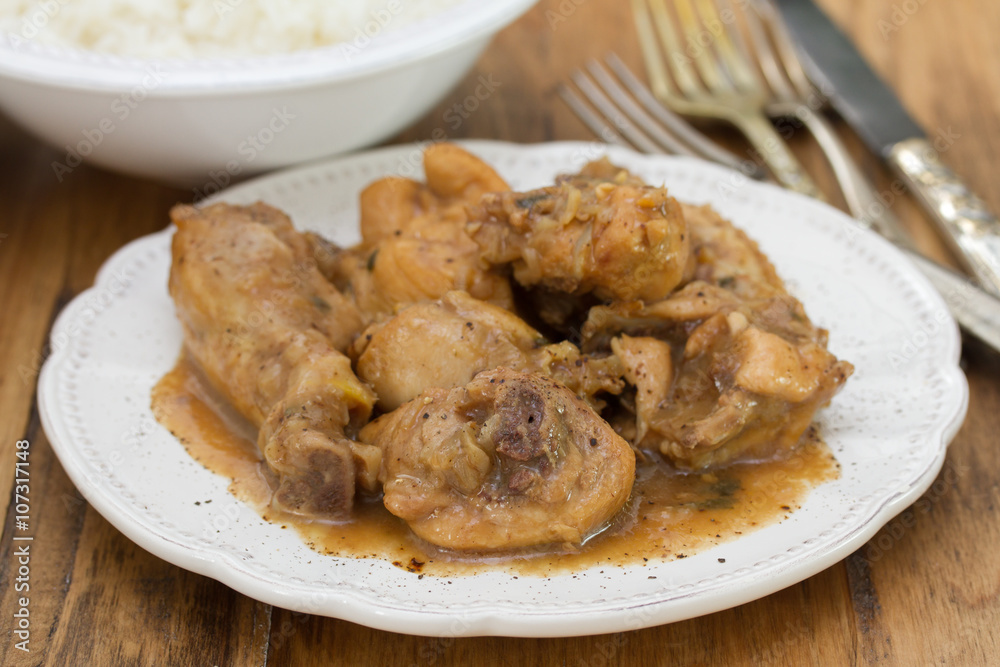 boiled chicken with beer sauce in white plate and rice in bowl on brown wooden background boiled chicken with beer sauce in white plate and rice in bowl on brown wooden background