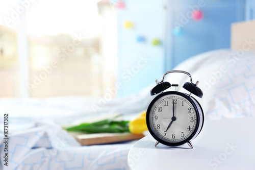 Vintage alarm clock on bedside table in a room