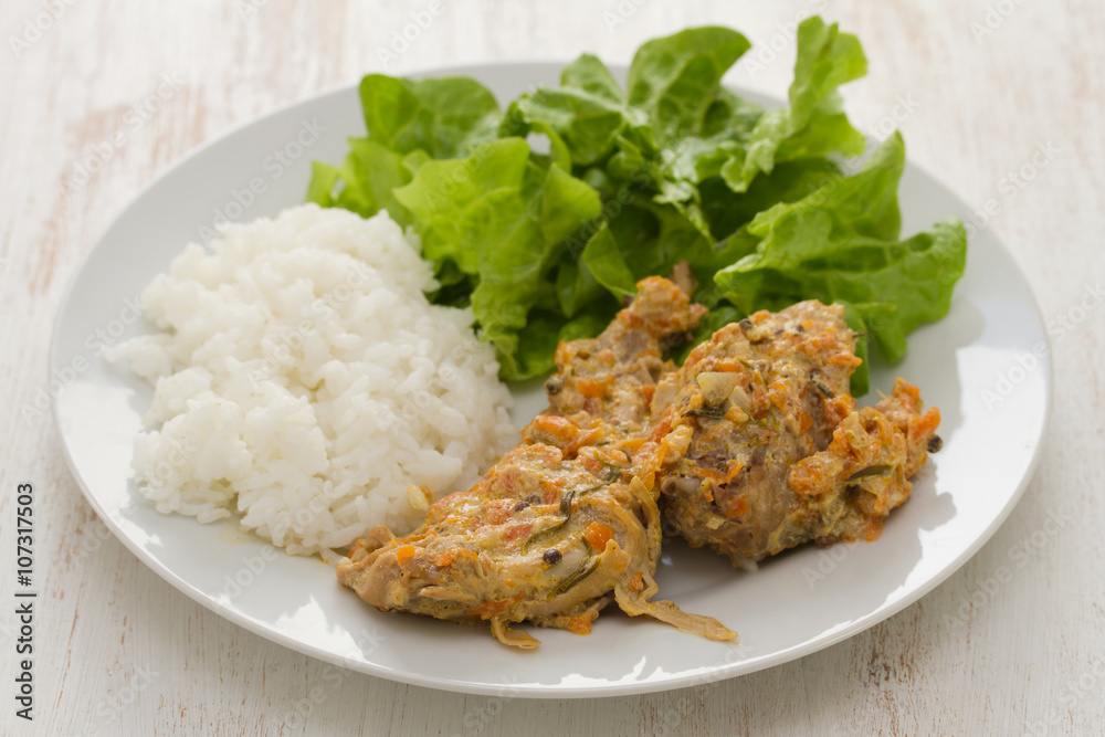 rabbit with boiled rice and salad on plate on white wooden background rabbit with boiled rice and salad on plate on white wooden background