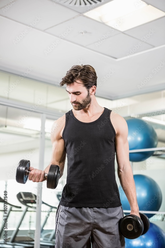 Concentrated man lifting dumbbells in the studio Concentrated man lifting dumbbells in the studio