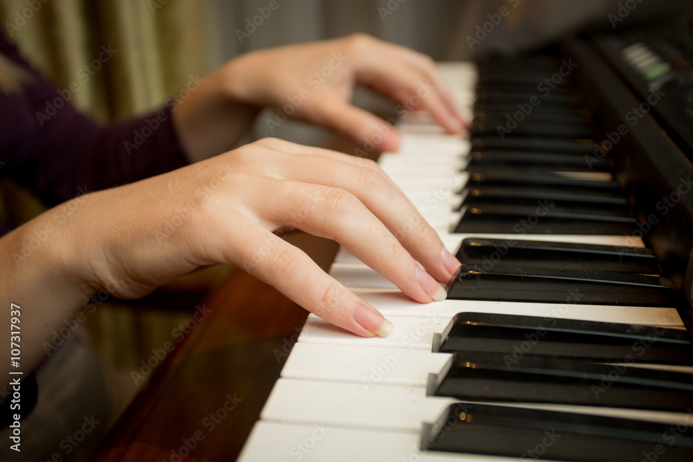 Closeup of young woman playing on piano