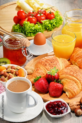 Breakfast consisting of croissants, coffee, fruits, orange juice