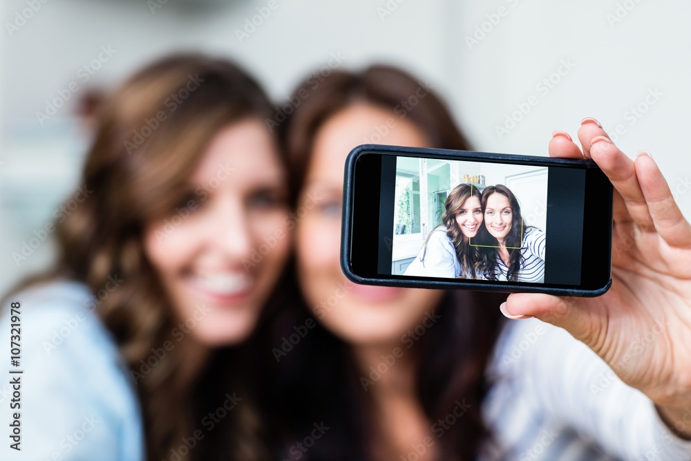 Smiling female friends photographing with smartphone 