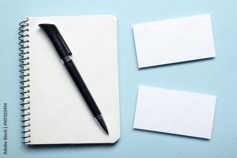 Business card blank over notepad at office table. Corporate stationery branding mock-up Business card blank over notepad at office table. Corporate stationery branding mock-up