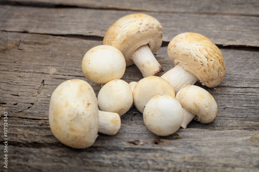 Stack of white button mushrooms, on wooden surface Stack of white button mushrooms, on wooden surface