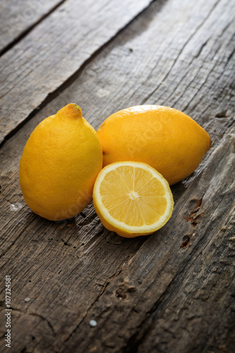 Two lemons and one half  on wooden surface