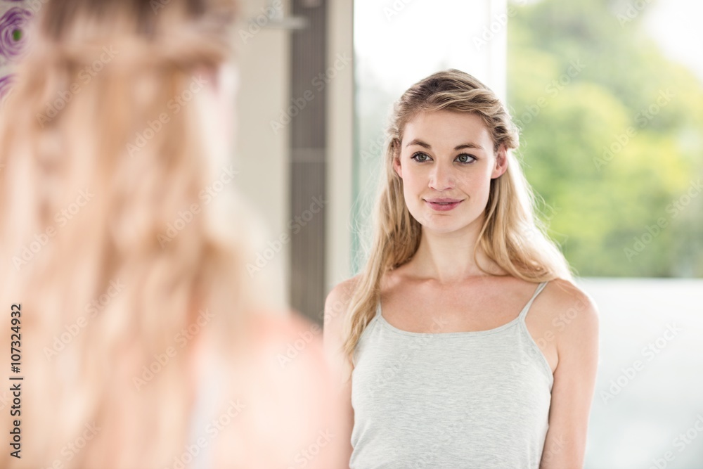 Confident young woman looking in mirror Confident young woman looking in mirror