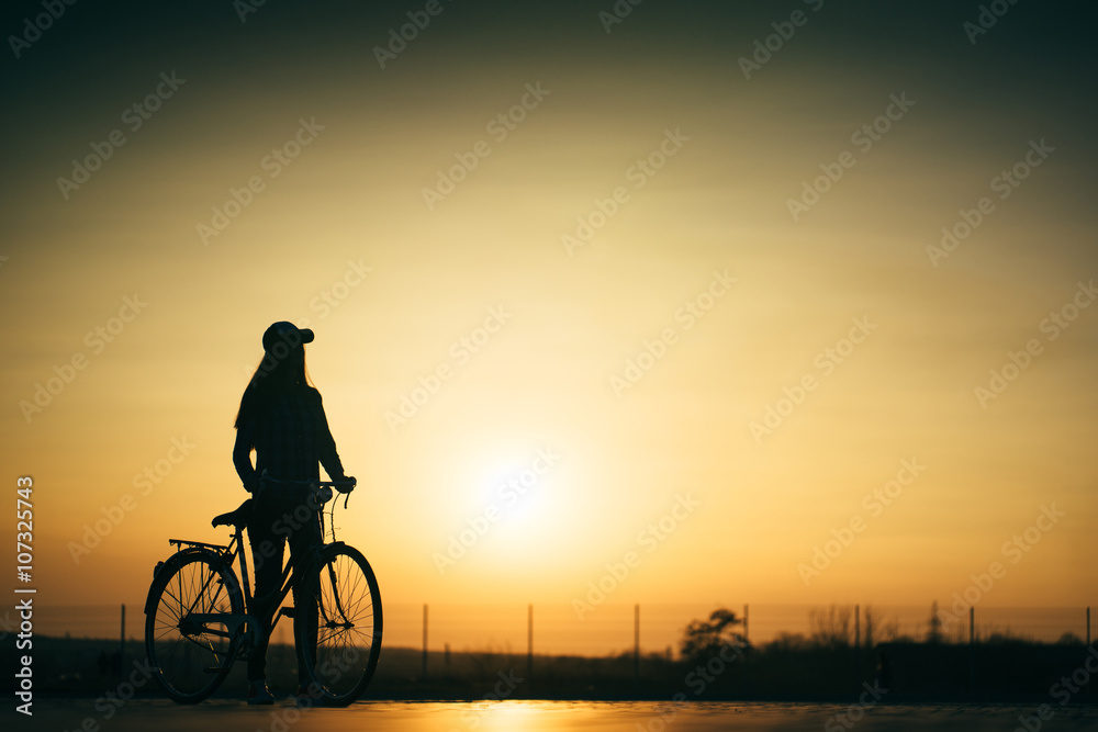 beautiful hipster girl with a bicycle on the road during sunset beautiful hipster girl with a bicycle on the road during sunset