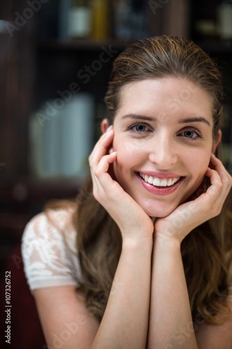 Smiling woman at restaurant with hands on chin