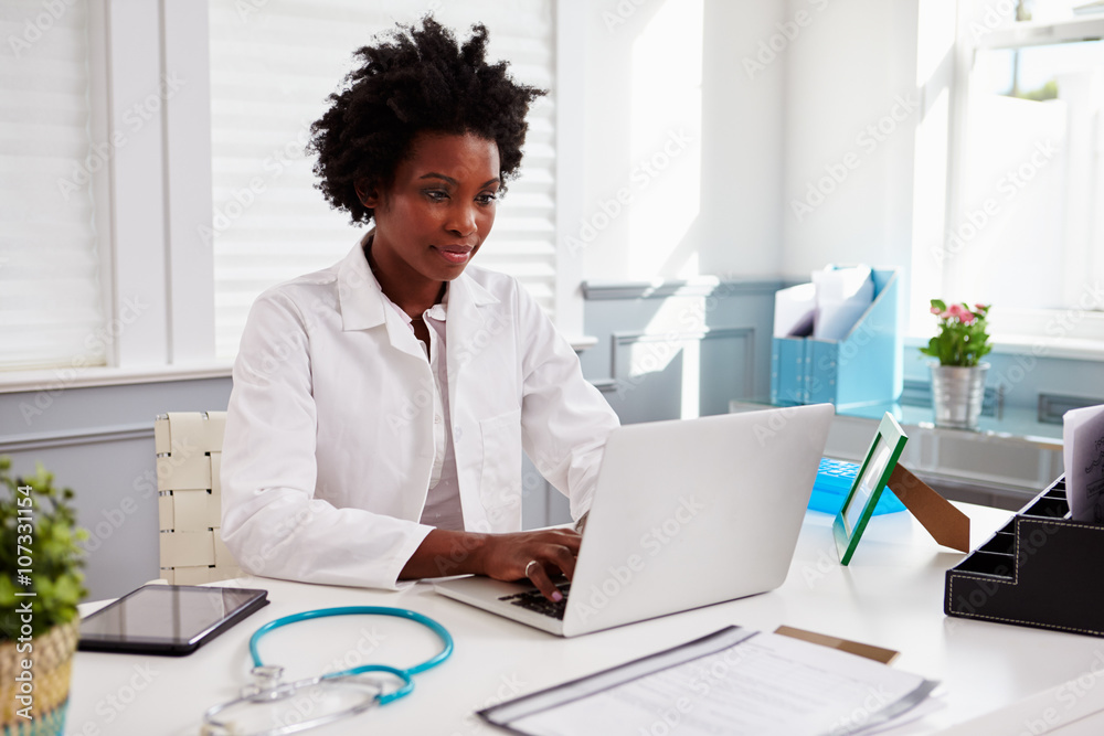 Black female doctor wearing white coat at work in an office Black female doctor wearing white coat at work in an office