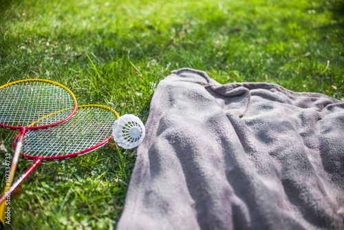 Shuttlecock and badminton racket and Blue picnic blanket on the grass field
