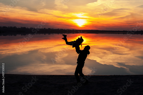 silhouette father with child on the lake at sunset