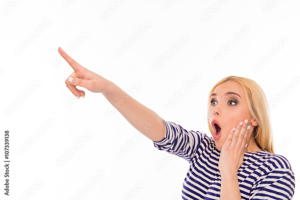 Wow! Shocked young woman pointing away and touching face Wow! Shocked young woman pointing away and touching face