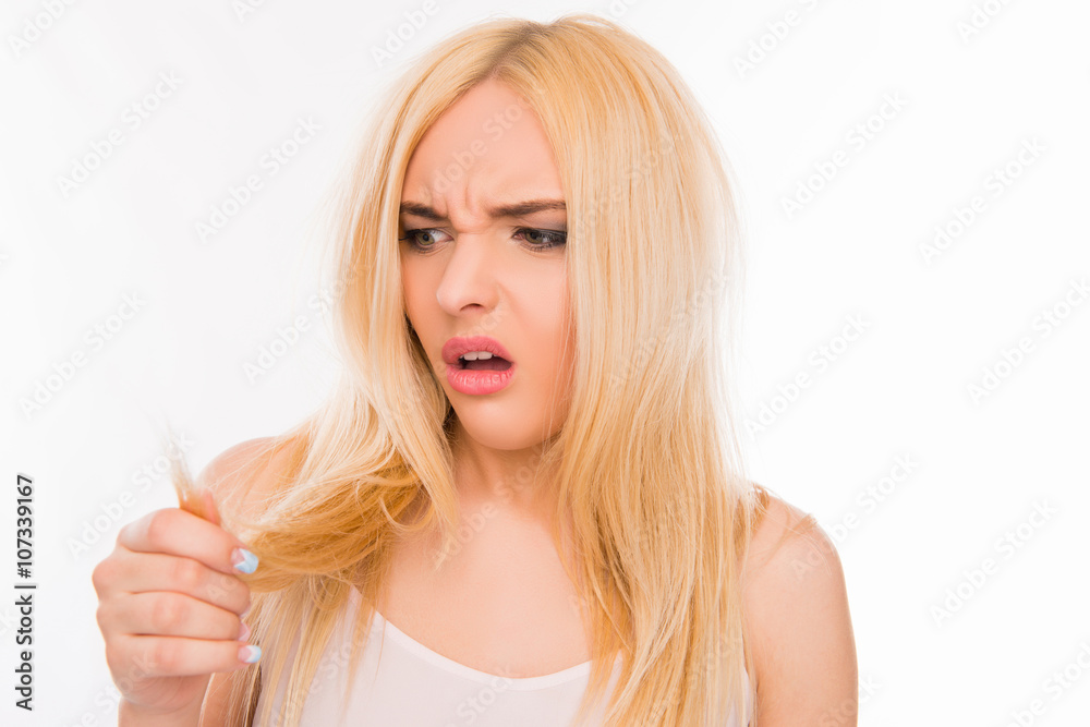Sad pretty girl looking at her damaged hair Sad pretty girl looking at her damaged hair