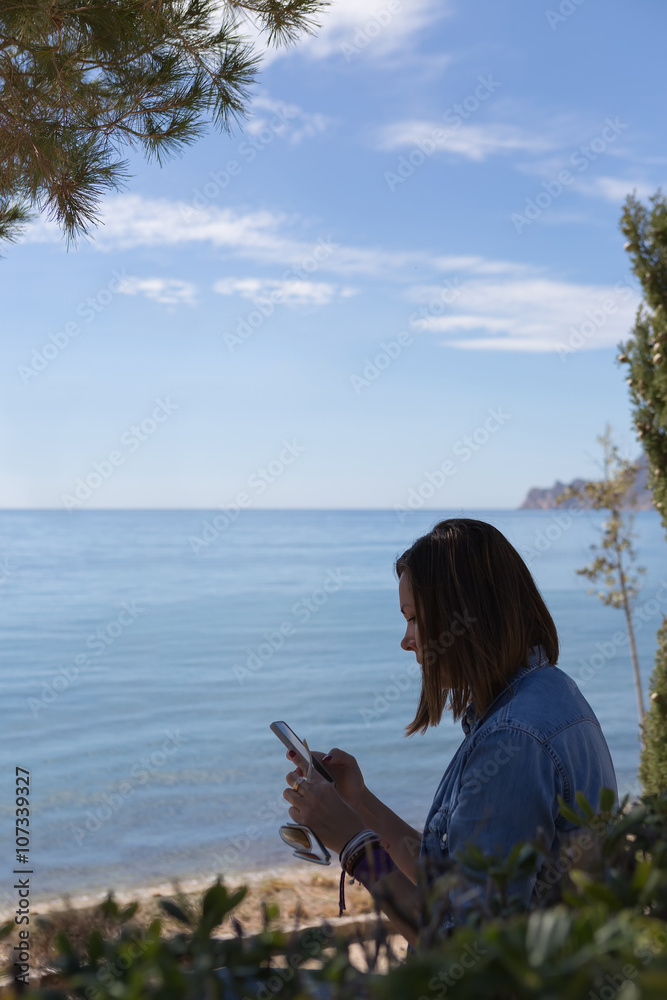 Naklejka premium Side view of black-haired woman with phone