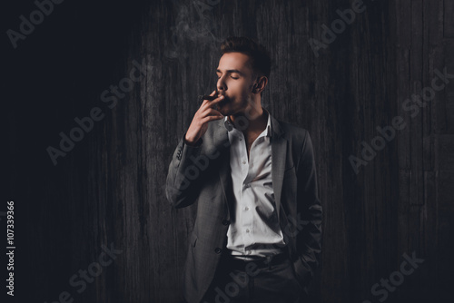 Portrait of serious young man in suit smoking a cigarette