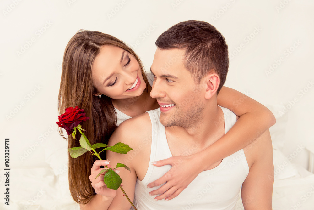 Cute happy couple in love embracing and holding red rose