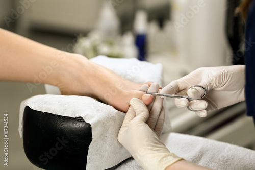 Cutting cuticle on foot  nail scissors. Pedicure process
