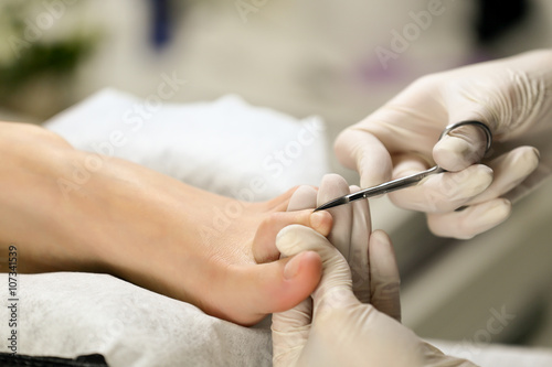 Close up Cutting cuticle on foot  nail scissors. Pedicure process