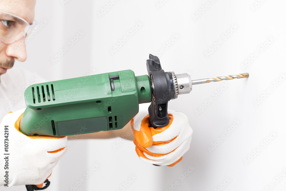 Young man drilling hole in wall Young man drilling hole in wall
