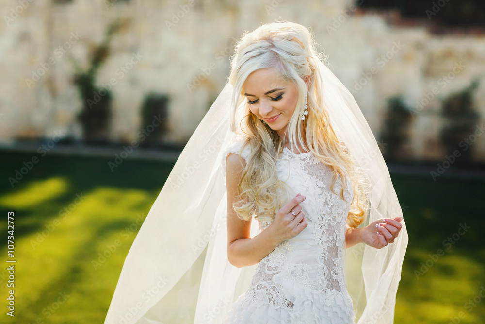 gently blonde bride in lace dress backgroung wall in garden gently blonde bride in lace dress backgroung wall in garden