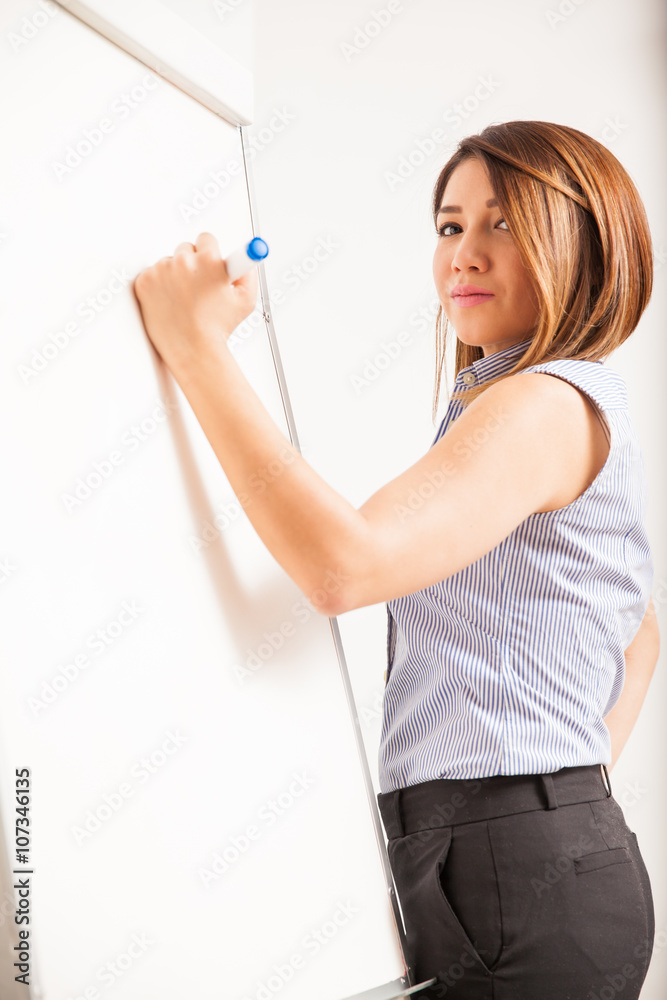 Cute female tutor writing on a whiteboard Cute female tutor writing on a whiteboard