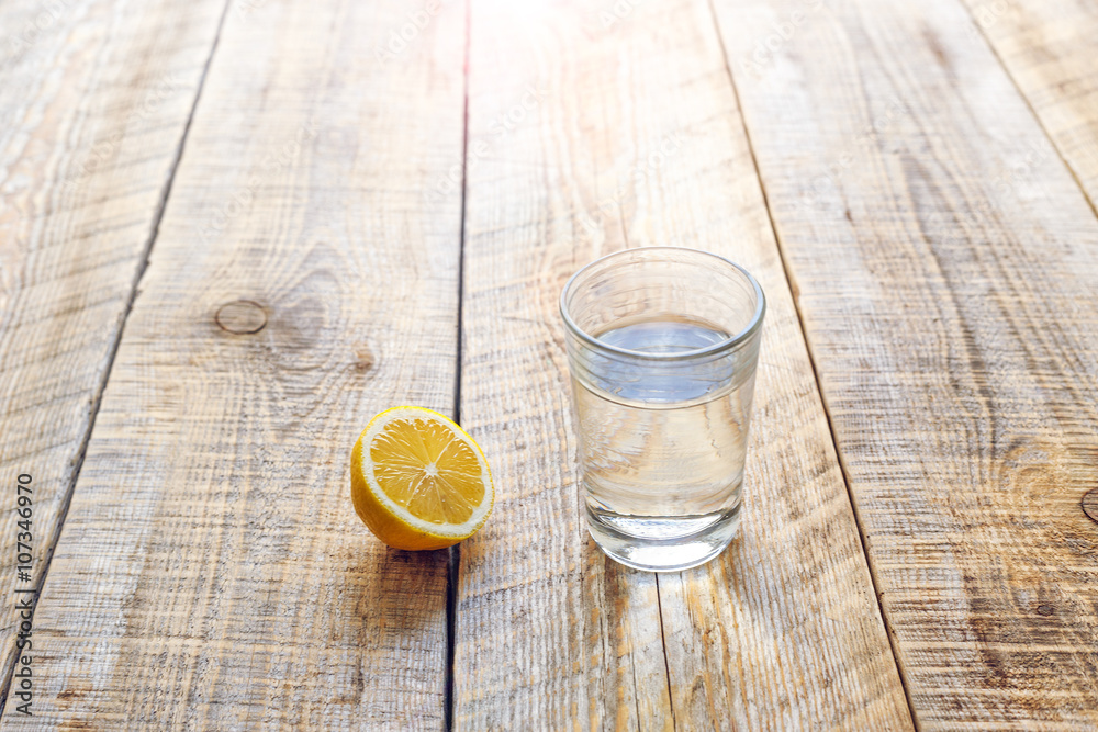 glass of fresh water with half lemon on wooden table glass of fresh water with half lemon on wooden table