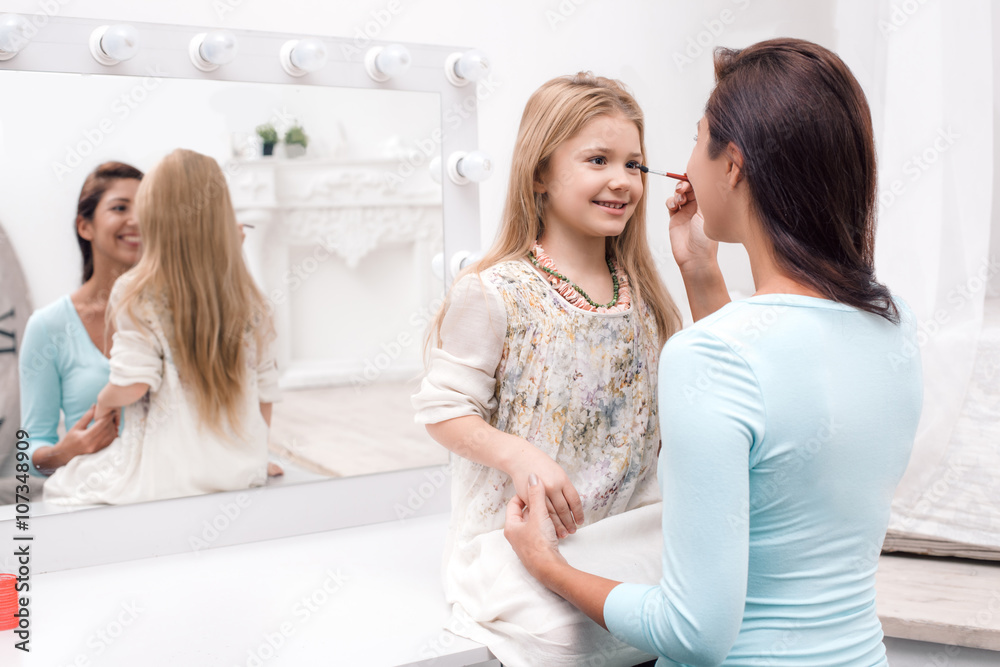 Mother and little daughter applying makeup