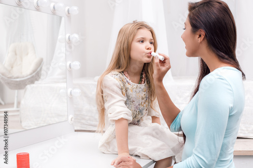 Mother and little daughter applying makeup