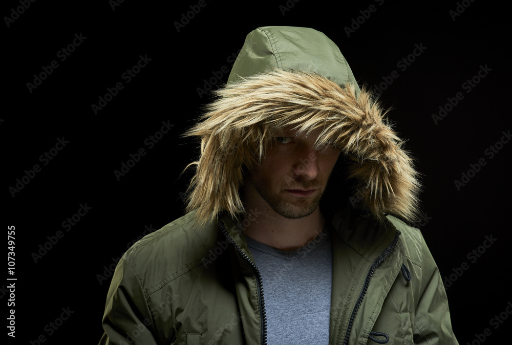 Low key studio portrait of suspicious young adult caucasian model wearing  winter coat with hood on. Stock Photo | Adobe Stock