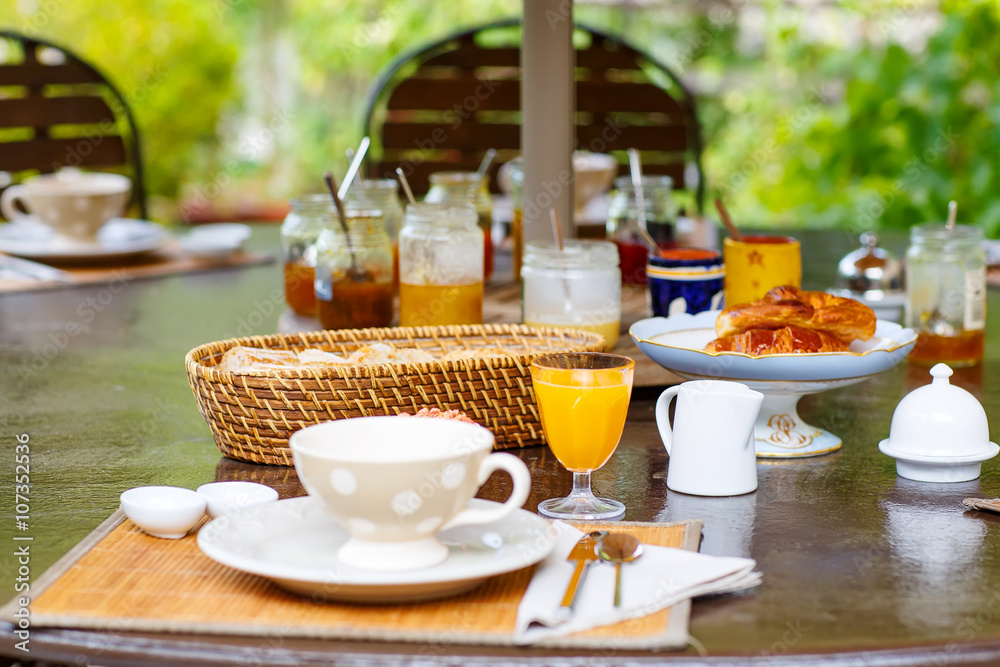 Table laid for breakfast outside with various jams coffee, crois