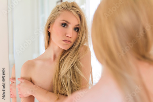 Portrait of sexy nude girl standing in front of the mirror, beauty boudoir concept
