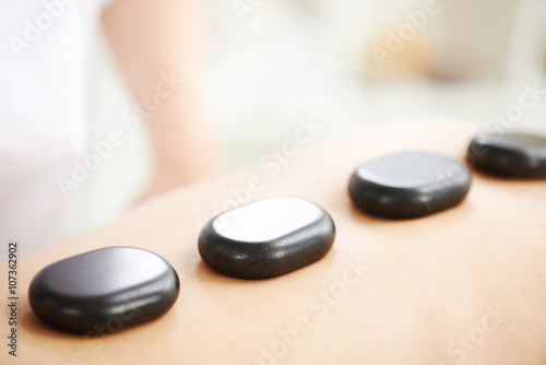 Woman having hot stones on her back in spa salon
