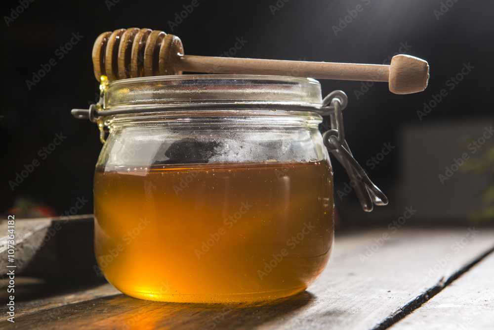 Miele italiano dentro vasetto di vetro con dosatore su sfondo legno Stock  Photo