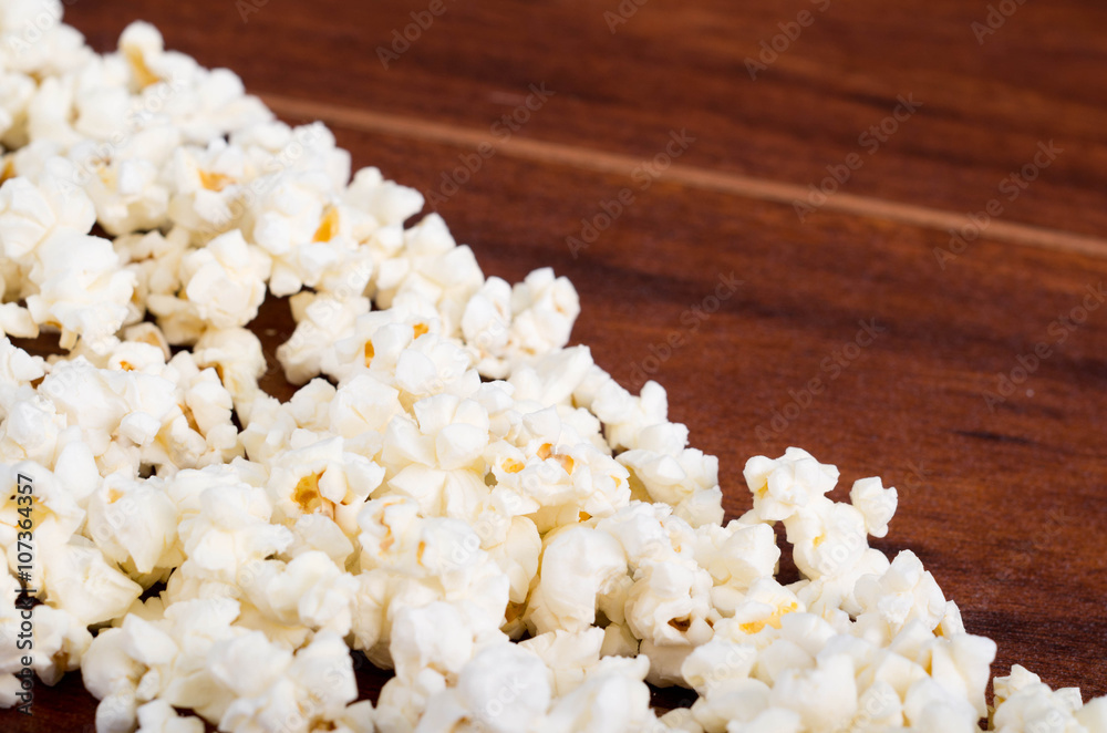 Closeup pile of white fluffy popcorn lying mixed together on wooden surface Closeup pile of white fluffy popcorn lying mixed together on wooden surface