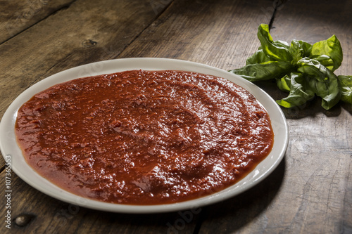 Sugo e basilico su piatto di porcellana posato su tavolo in legno photo