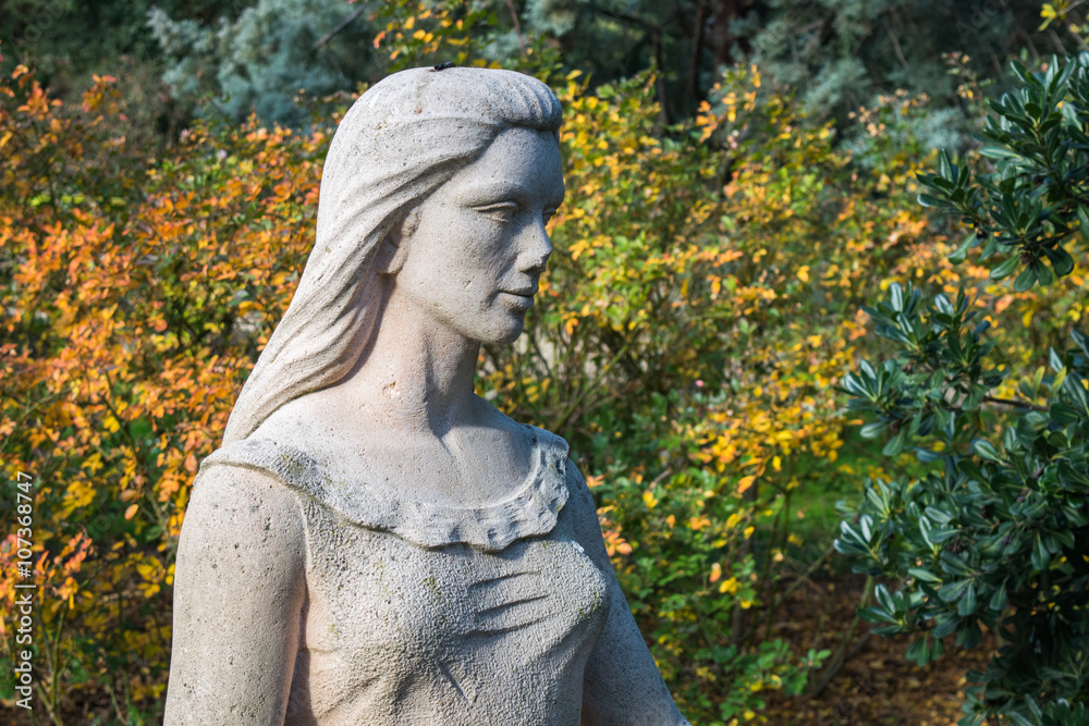 statue of a woman with background of colorful leaves