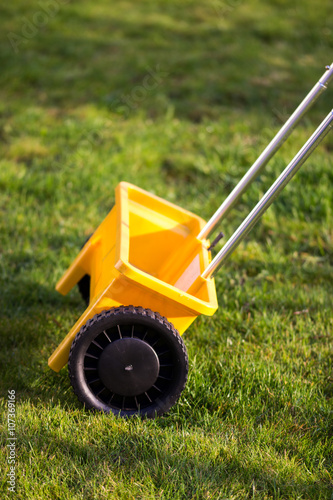 Rasen Gras düngen mit gelbem Streuwagen