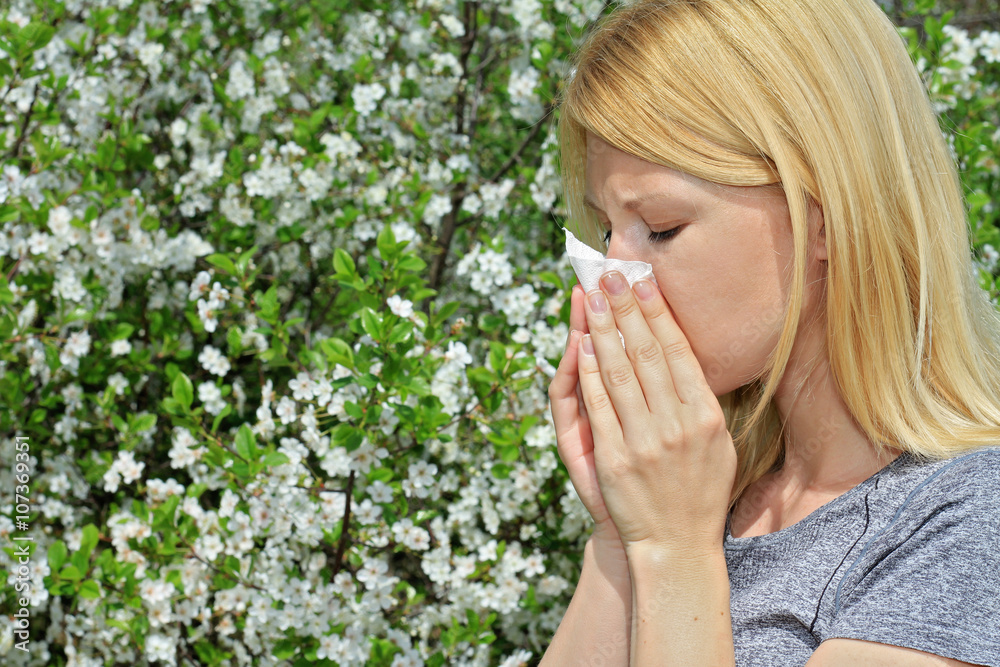 Pollen allergy, Springtime. Woman sneezing in a tissue Pollen allergy, Springtime. Woman sneezing in a tissue
