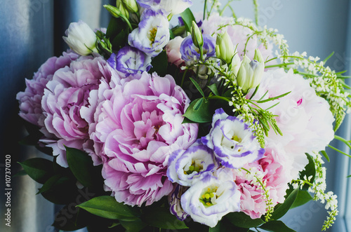 Rich bunch of pink peonies peony and lilac eustoma roses flowers. Rustic style, still life. Fresh spring bouquet, pastel colors. Background.
