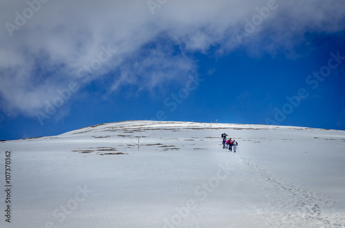 Winter landscape in the mountains. Group of hikers. Mountain ridges covered by snow in  winter in Europe.