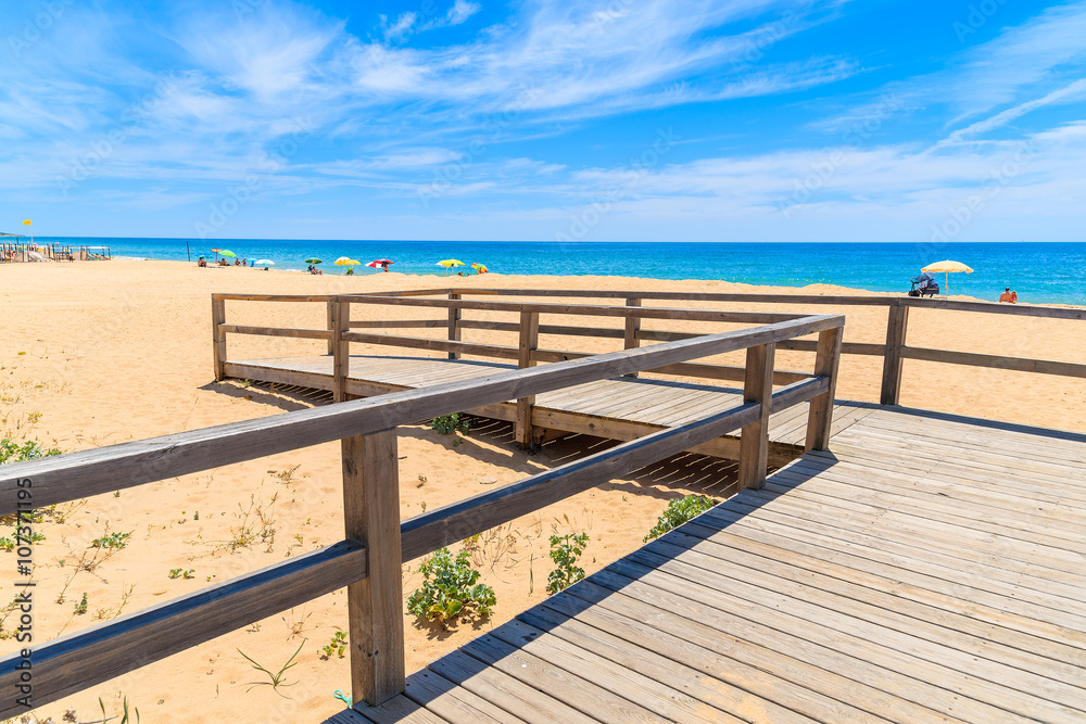 Wooden footbridge to sandy beach in Armacao de Pera coastal town, Algarve region, Portugal