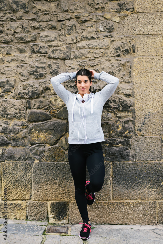 Sporty woman tying ponytail and getting ready for urban outdoor workout. Female runner on a training rest. Sporty woman tying ponytail and getting ready for urban outdoor workout. Female runner on a training rest.