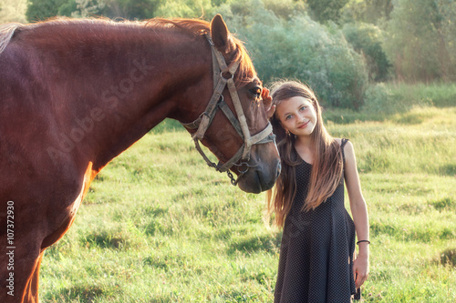 Girl stroking her horse and looking at the camera