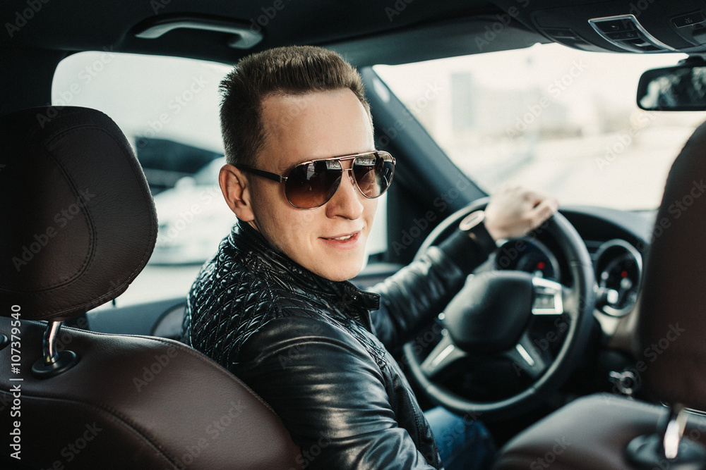 Fashionable Handsome Man in Sunglasses Sitting in his Luxury on Driver Seat. Luxury Life. Lifestyle photo. Ideal for commercial. Rental car concept Fashionable Handsome Man in Sunglasses Sitting in his Luxury on Driver Seat. Luxury Life. Lifestyle photo. Ideal for commercial. Rental car concept